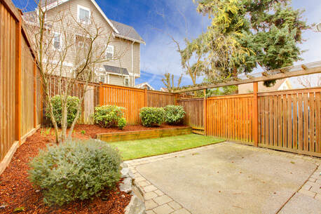 backyard concrete patio with stone masonry and wooden privacy fence