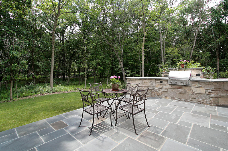 blue stone masonr ybackyard patio and grill built into stone wall