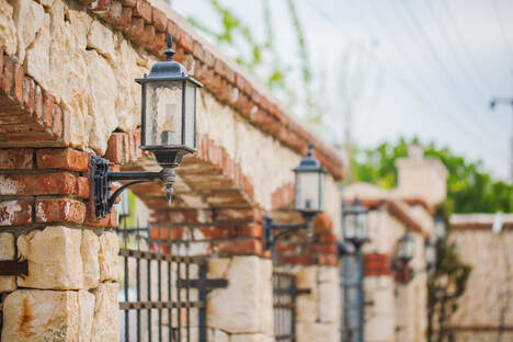 brick and stone wall composite masonry with iron fencing and light fixtures