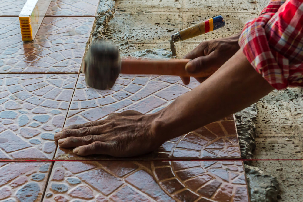 mason isntalling decorastive floor tiling