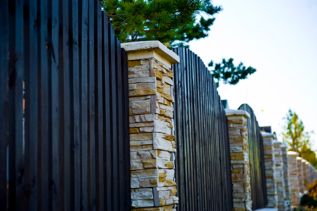 rough tooled stone masonry columns ibetween wooden fences