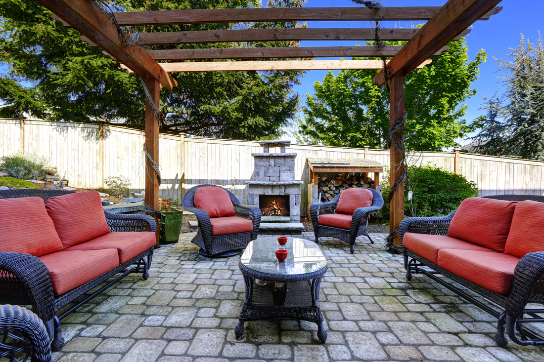 stone patio with red cushions and outdoor fireplace